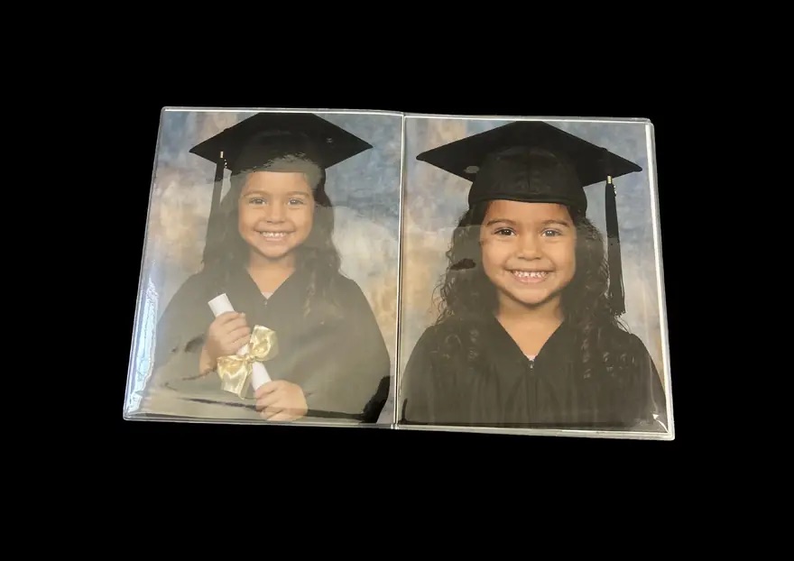 Open book spread showing two 25 by 20 centimetre portraits of the child photographed in cap and gown