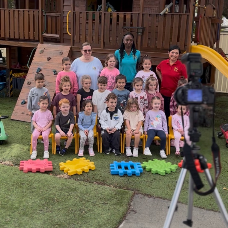 A Little Images photographer setting up a class group photo in a centre playground