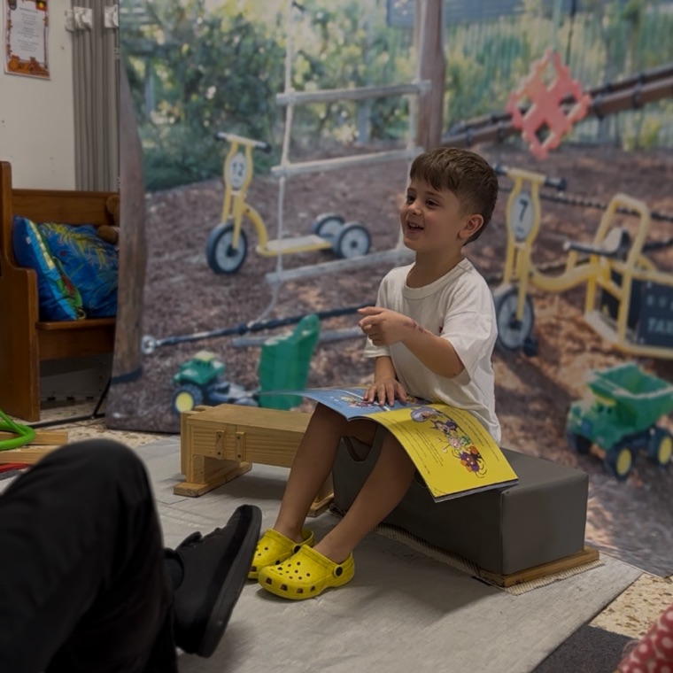 A child smiling and pointing at the camera in the photo booth setup